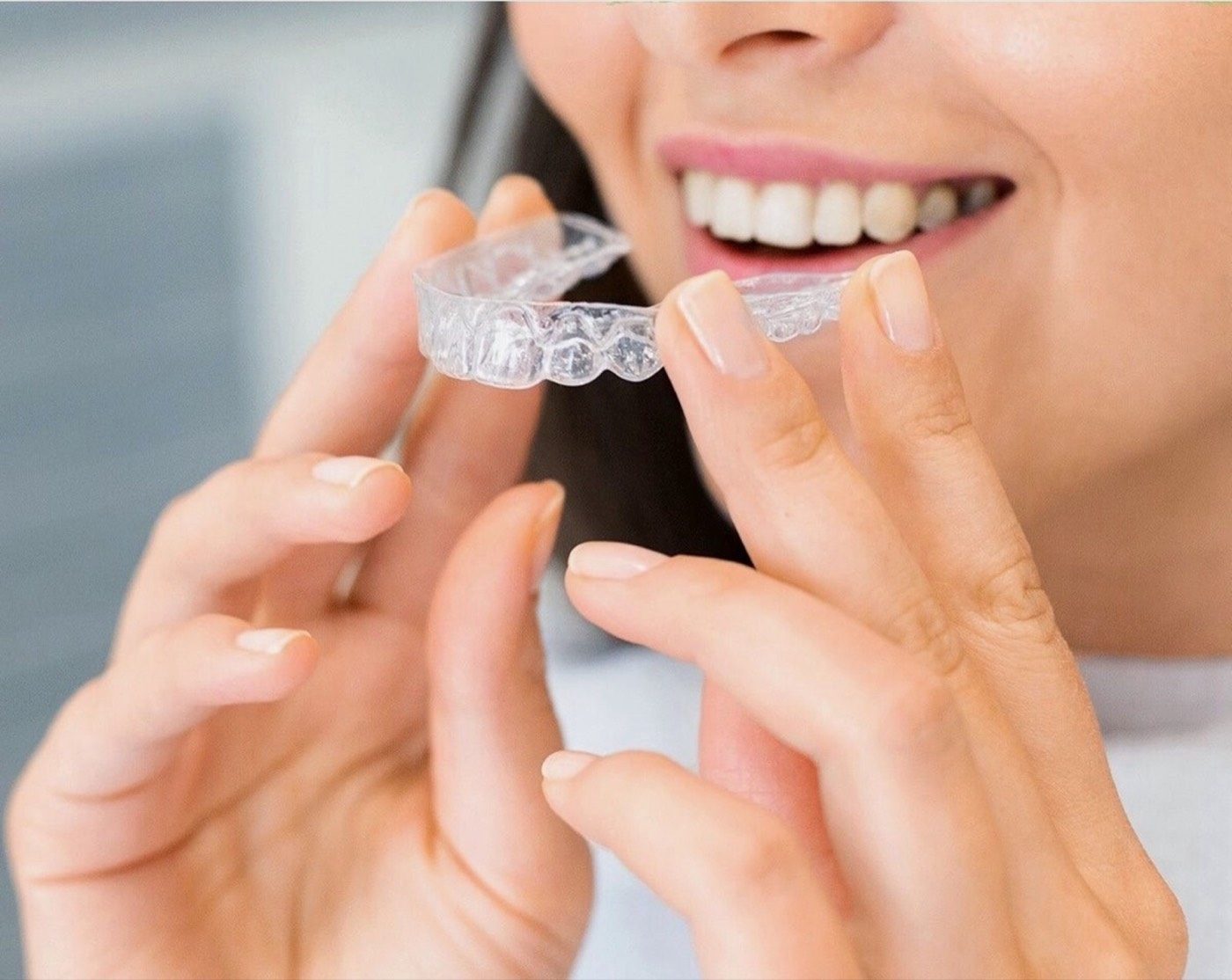 A patient placing a clear aligner over their teeth